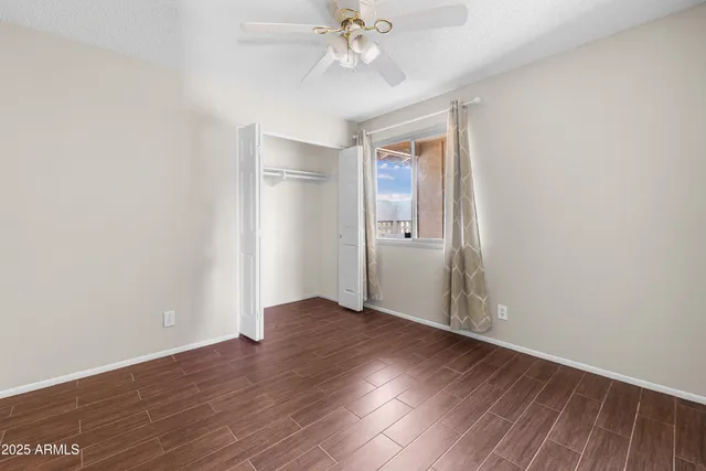 an empty room with wooden floor chandelier fan and windows