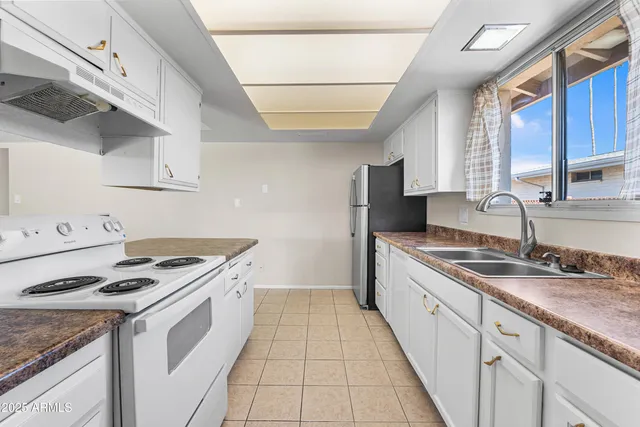 a kitchen with granite countertop a sink stove a refrigerator and cabinets