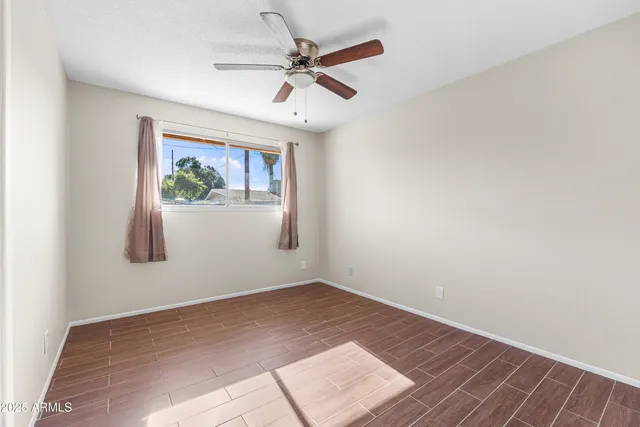 an empty room with a window and a ceiling fan