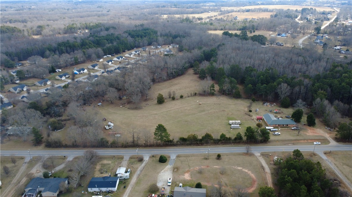 6980 Midway Road Pelzer, SC 29669 - Photo 15 of 15 This aerial view showcases a residential community nestled among fields and woodlands, offering ample space and tranquility.