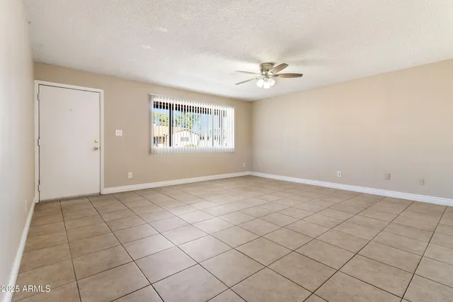 an empty room with windows and fan