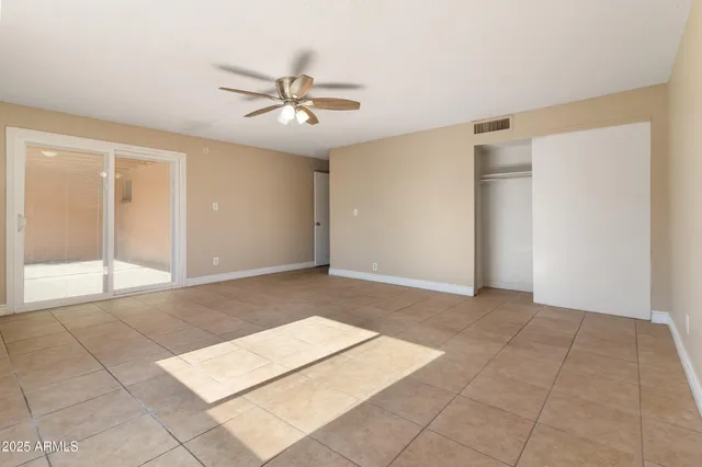 a view of an empty room with window and chandelier fan