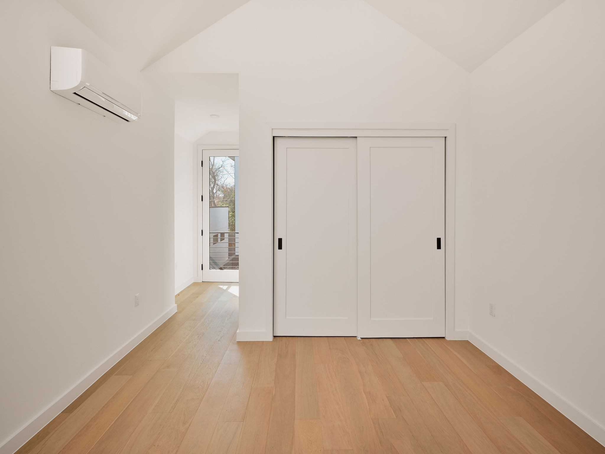 3209 Dolphin Drive, Unit 2 Austin, TX 78704 - Photo 21 of 28 Unfurnished bedroom with vaulted ceiling, light wood-type flooring, a wall mounted air conditioner, and a closet
