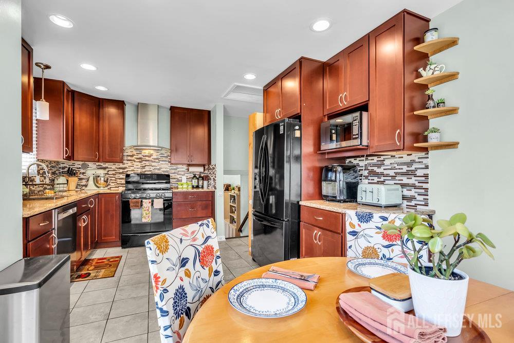 14 Academic Road East Brunswick, NJ 08816 - Photo 12 of 28 a kitchen with stainless steel appliances wooden floor dining table and chairs
