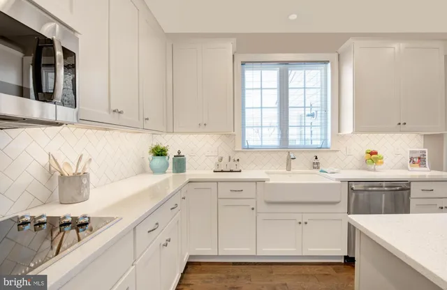 a kitchen with a sink dishwasher a stove and white cabinets with wooden floor