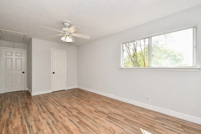 a view of empty room with wooden floor and fan