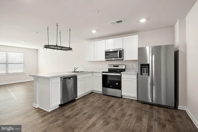 a kitchen with a refrigerator stove and wooden floor