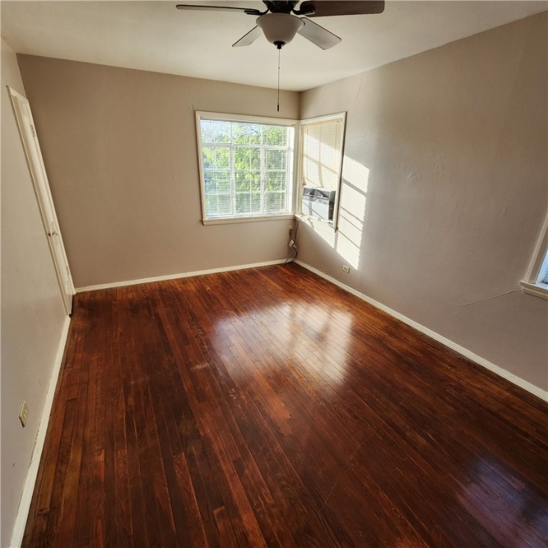 243 Indiana Avenue, Unit 5 Corpus Christi, TX 78404 - Photo 2 of 4 an empty room with wooden floor chandelier fan and windows