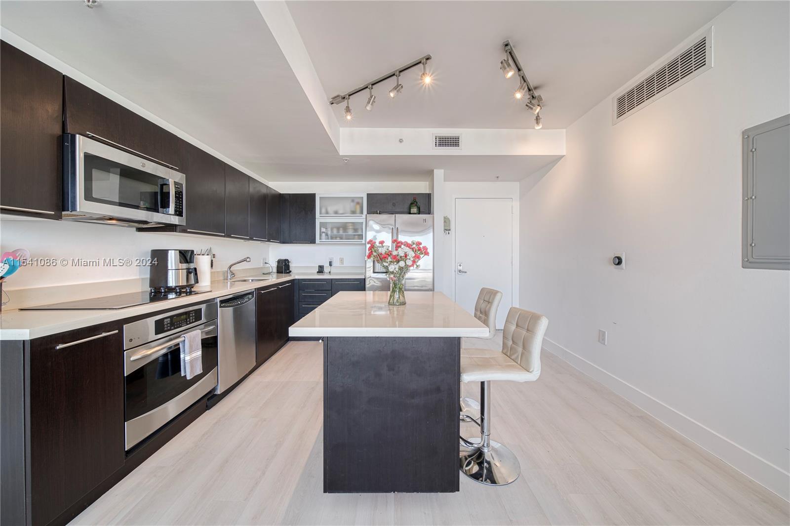 a kitchen with stainless steel appliances kitchen island granite countertop a table chairs in it and a window