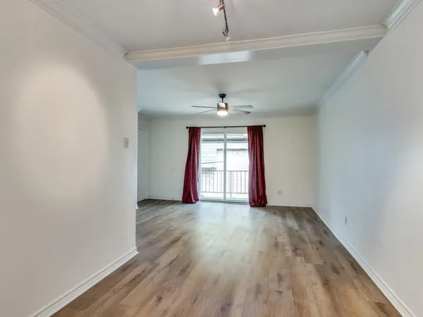 a view of an empty room with window and wooden floor