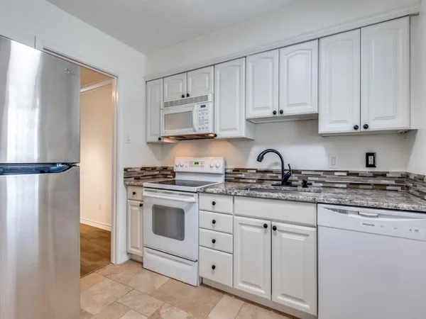 a kitchen with granite countertop white cabinets and stainless steel appliances