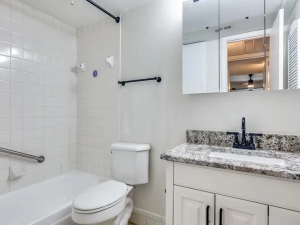 a bathroom with a granite countertop sink a toilet and mirror