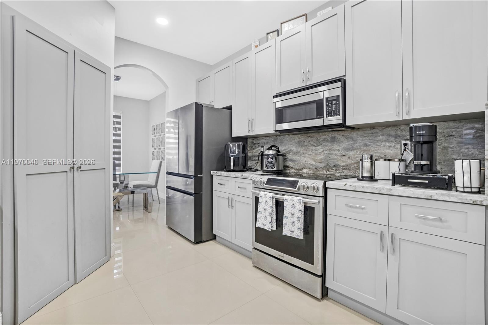 2132 Northeast 38th Road Homestead, FL 33033 - Photo 7 of 48 a kitchen with stainless steel appliances granite countertop white cabinets a refrigerator and a stove top oven