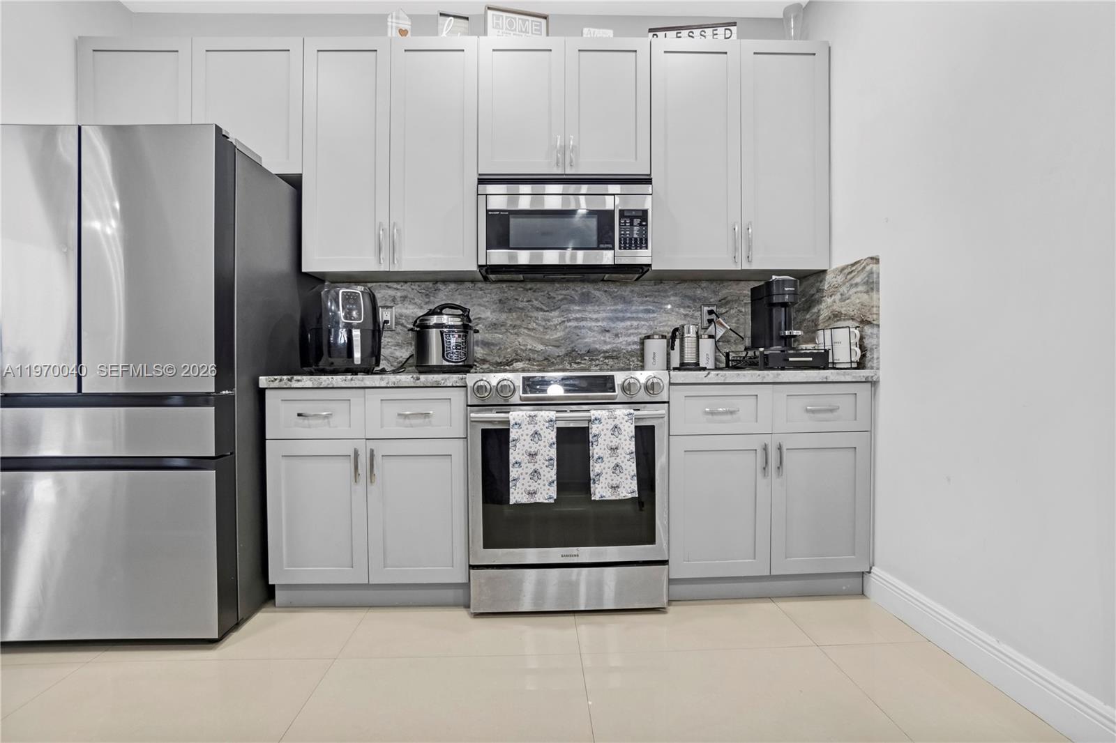 2132 Northeast 38th Road Homestead, FL 33033 - Photo 10 of 48 a kitchen with stainless steel appliances granite countertop a refrigerator stove and white cabinets