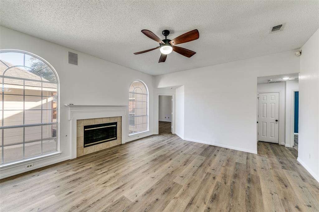 1913 Smith Drive Plano, TX 75023 - Photo 2 of 12 an empty room with wooden floor a ceiling fan and windows