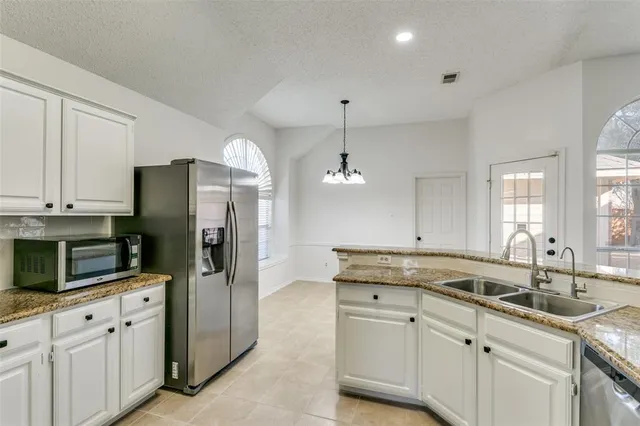 a kitchen with granite countertop a sink stainless steel appliances and white cabinets