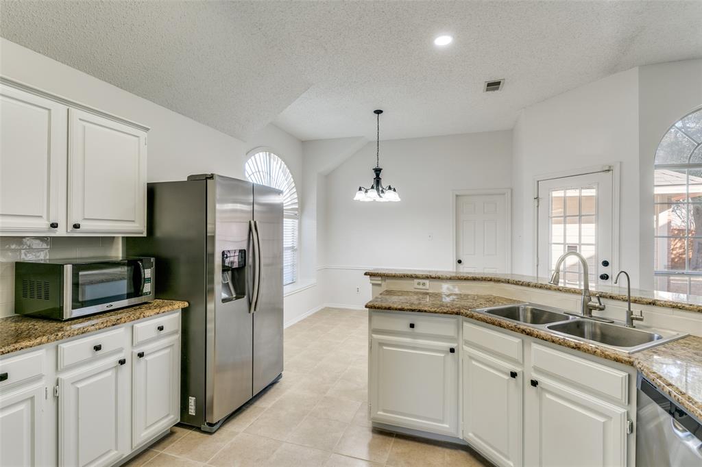 1913 Smith Drive Plano, TX 75023 - Photo 5 of 12 a kitchen with granite countertop a sink stainless steel appliances and white cabinets