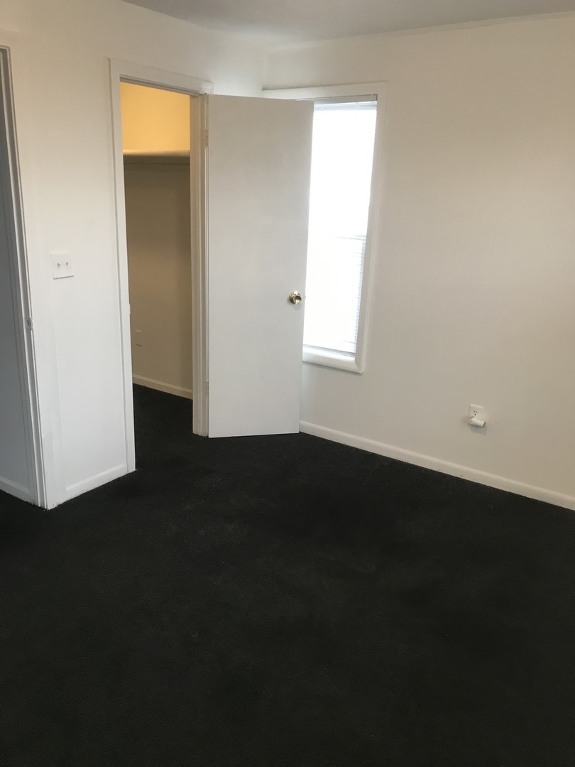 3929 Main Street, Unit 2 McHenry, IL 60050 - Photo 10 of 17 a view of an empty room with wooden floor and a window