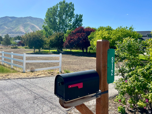 812 East Bates Cyn Road Tooele, UT 84074 - Photo 2 of 144 Property entrance featuring a black mailbox on a wooden post with an address marker, bordered by a white fence