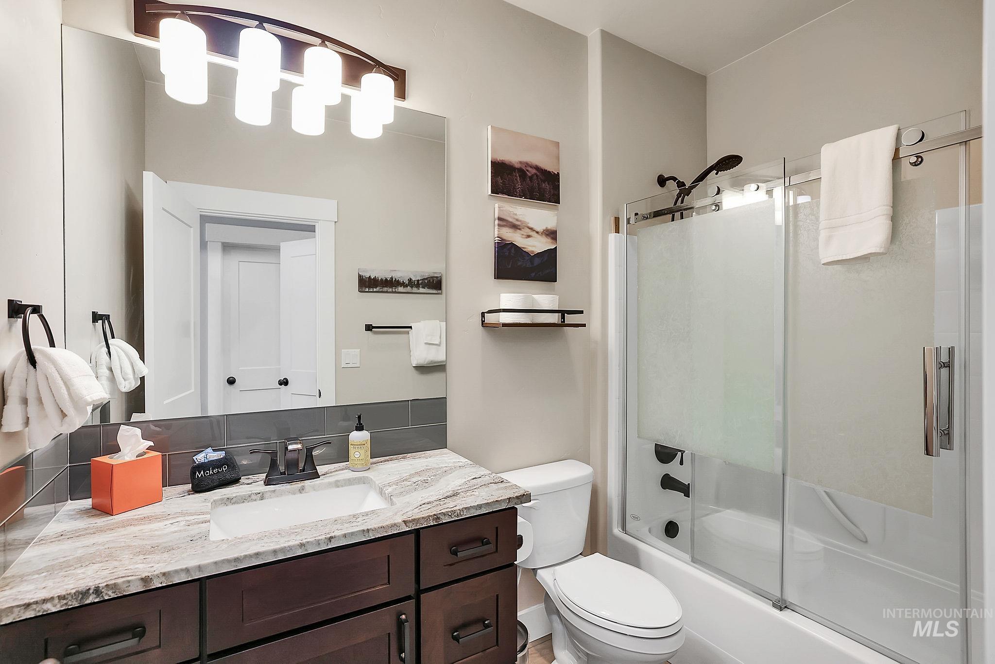 609 Blue Water Circle McCall, ID 83638 - Photo 20 of 45 Full bathroom featuring vanity, bath / shower combo with glass door, and decorative backsplash