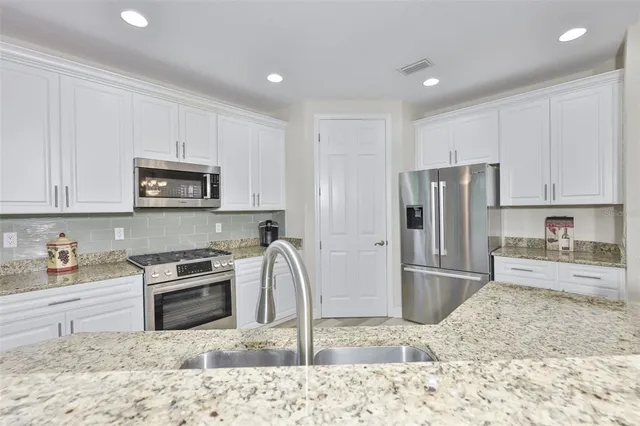a kitchen with granite countertop a refrigerator and a sink