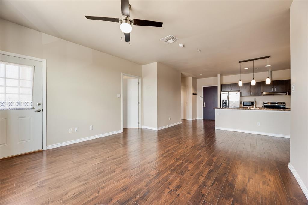 1100 West Trinity Mills Road, Unit 2040 Carrollton, TX 75006 - Photo 7 of 21 a view of an empty room and kitchen with wooden floor