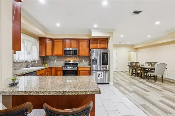 a kitchen with stainless steel appliances granite countertop a stove a sink a refrigerator and chairs