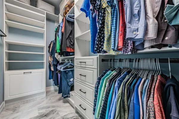 a view of walk in closet with clothes and shoes