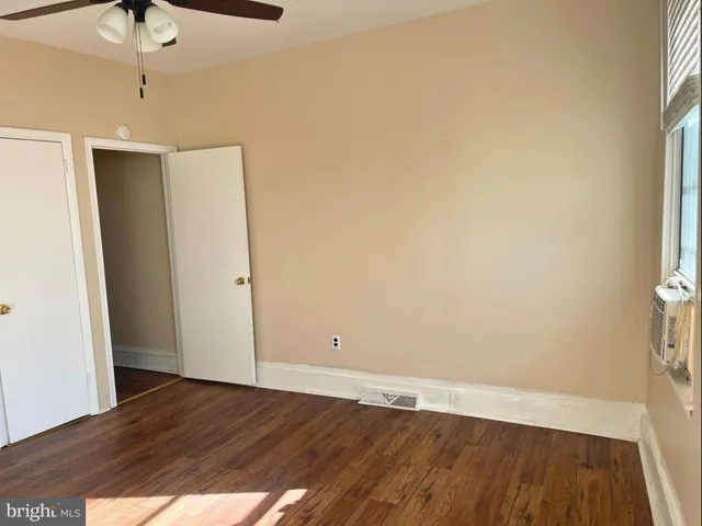 an empty room with wooden floor fan and windows