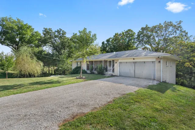 a view of a house with a yard and large trees