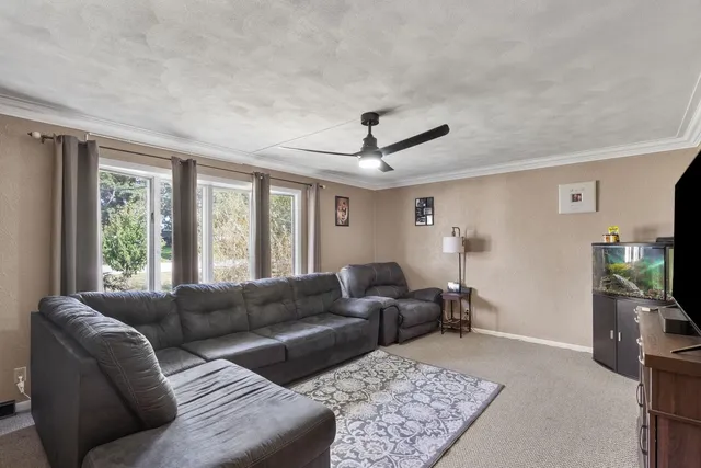 a living room with furniture a flat screen tv and a large window