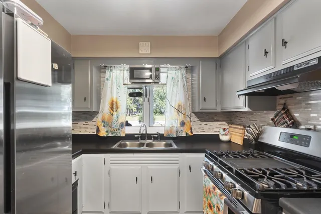 a kitchen with stainless steel appliances granite countertop a stove a sink dishwasher and cabinets with wooden floor