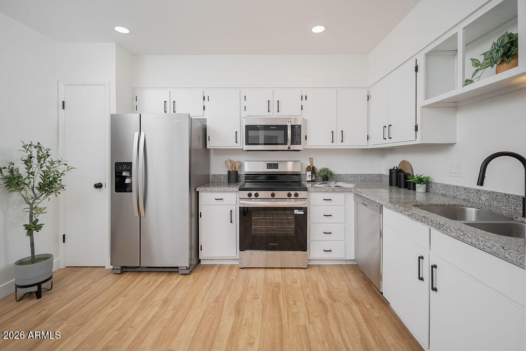720 South Dobson Road, Unit 85 Mesa, AZ 85202 - Photo 2 of 16 a kitchen with granite countertop a refrigerator stove and white cabinets
