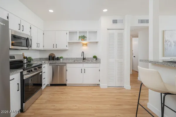 a kitchen with stainless steel appliances white cabinets and wooden floor