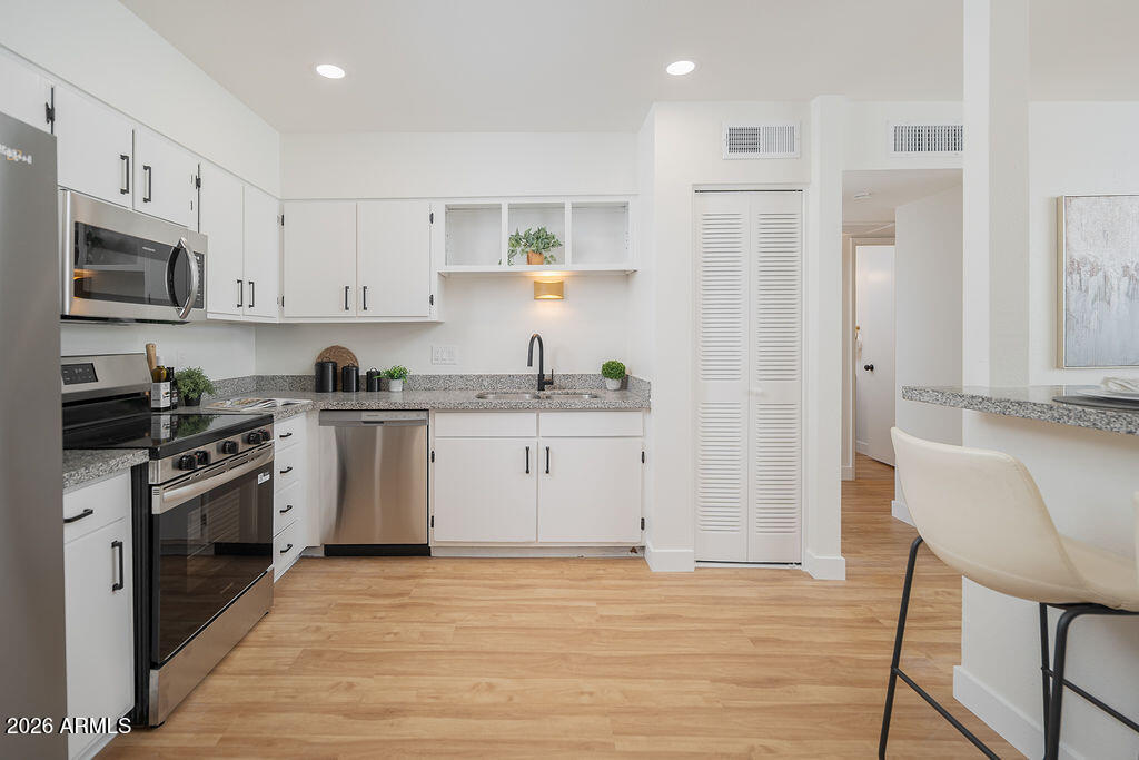 720 South Dobson Road, Unit 85 Mesa, AZ 85202 - Photo 4 of 16 a kitchen with stainless steel appliances white cabinets and wooden floor