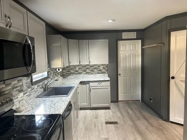 a kitchen with kitchen island granite countertop a sink stove and refrigerator