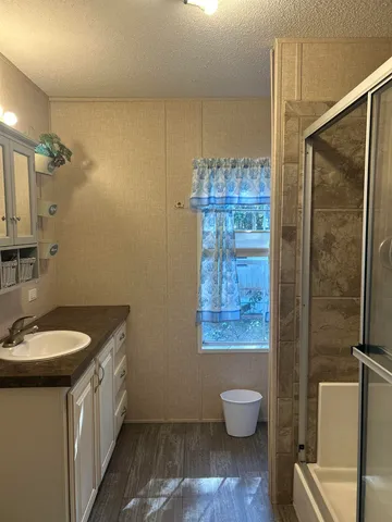 a bathroom with a granite countertop sink a toilet a mirror and shower