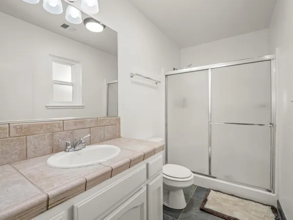 a bathroom with a granite countertop sink toilet a mirror and shower