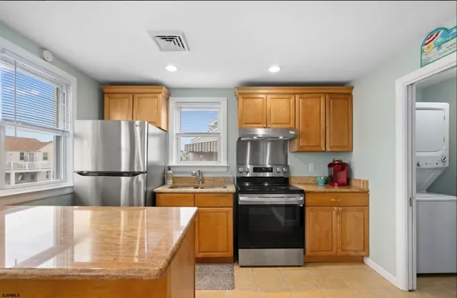 a kitchen with kitchen island granite countertop a stove top oven sink and a refrigerator