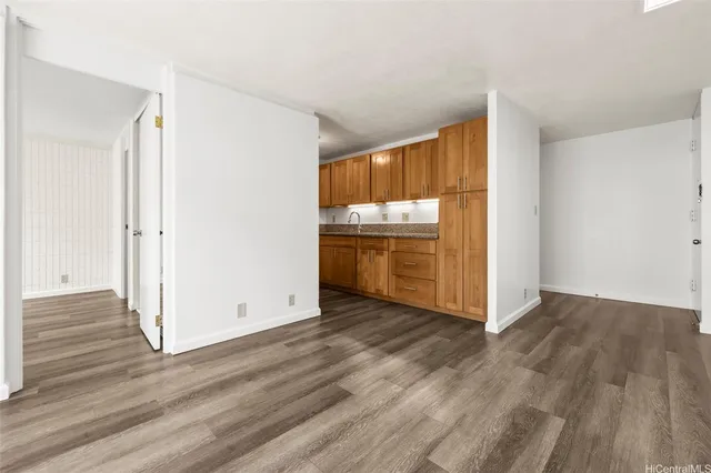 an empty room with wooden floor cabinet and windows