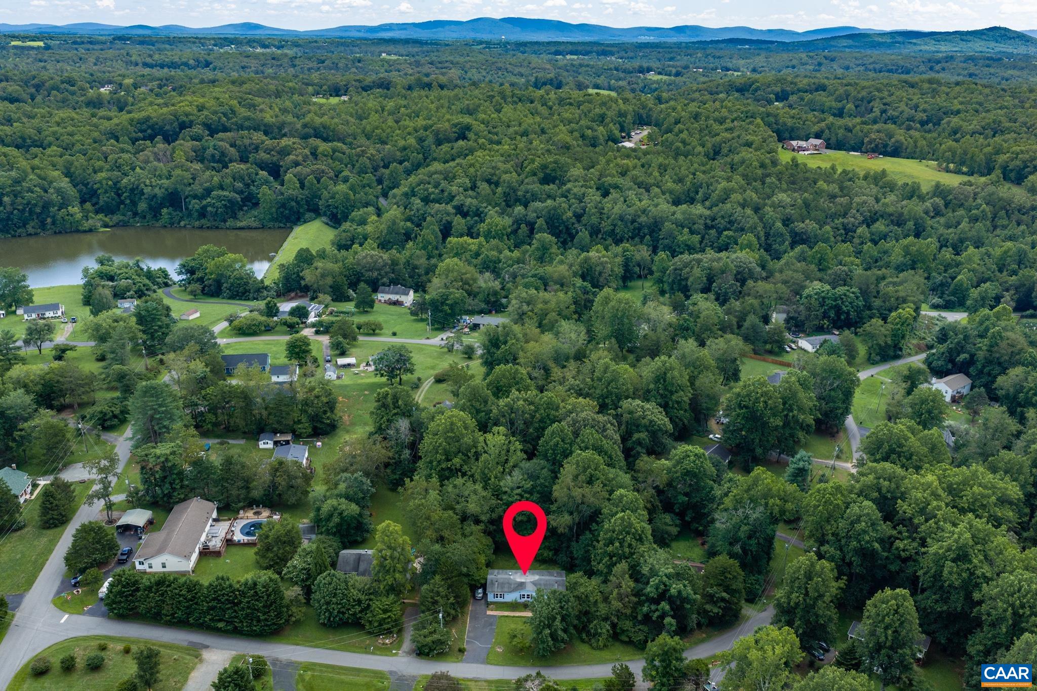 61 Snapdragon Road Ruckersville, VA 22968 - Photo 43 of 47 Pinpointed in a peaceful neighborhood setting! This aerial view showcases the home's lush, tree-lined lot, nearby water features, and scenic distant hills. Enjoy a tranquil community lifestyle surrounded by nature's beauty!