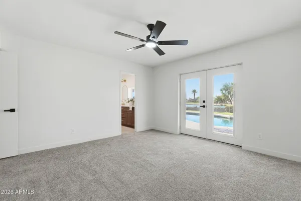 an empty room with a ceiling fan and carpet