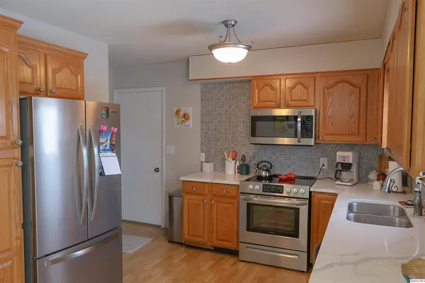 a kitchen with stainless steel appliances granite countertop a refrigerator a stove a sink and a microwave