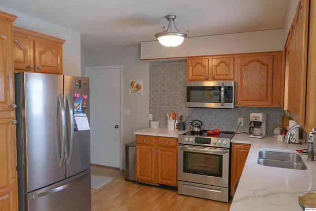 a kitchen with stainless steel appliances granite countertop a refrigerator a stove a sink and a microwave