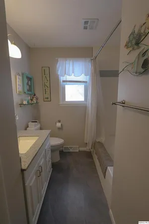 a spacious bathroom with a granite countertop sink a toilet a shower and a mirror