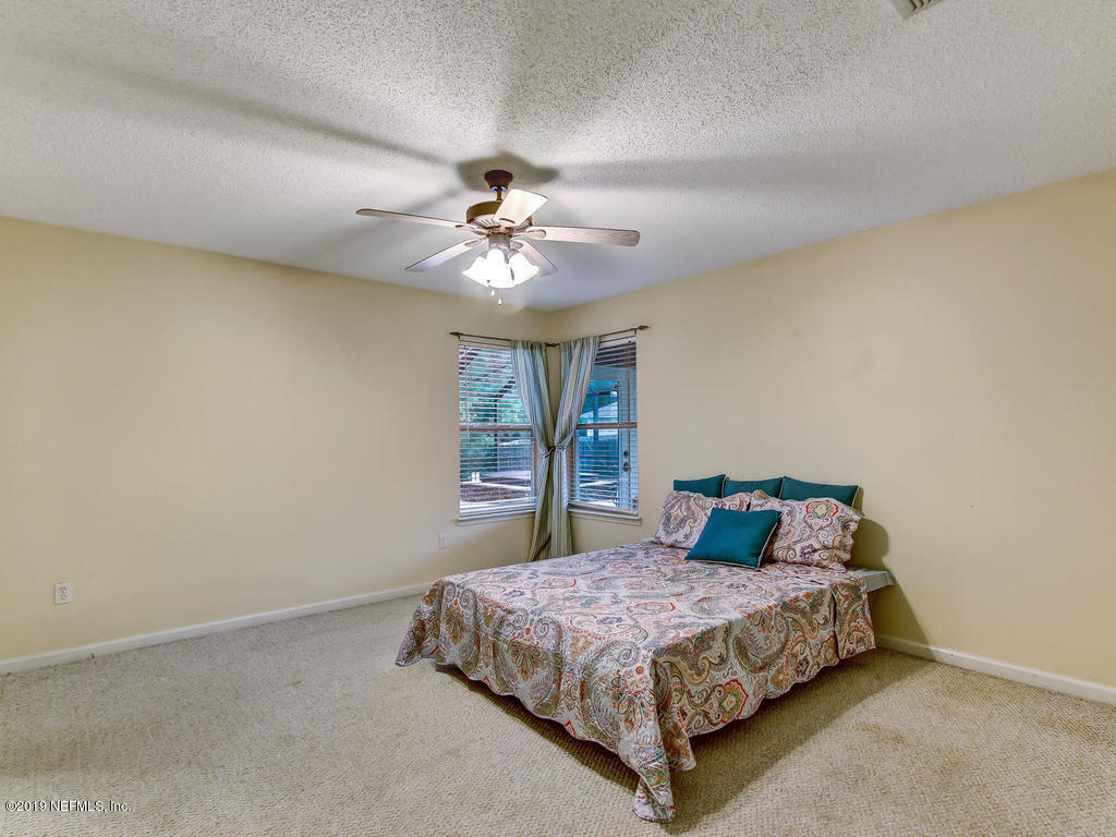 573 Prosperity Lake Drive St. Augustine, FL 32092 - Photo 11 of 23 a bedroom with a large bed and a chandelier
