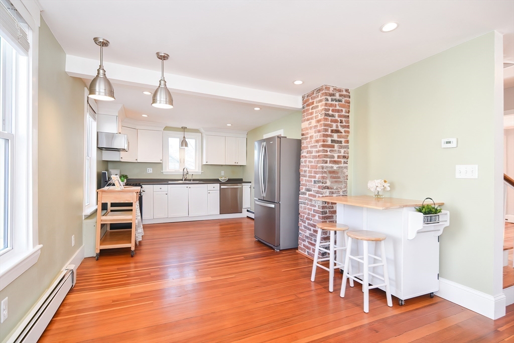 58 Holmes Road Dedham, MA 02026 - Photo 8 of 29 a kitchen with stainless steel appliances kitchen island granite countertop a table chairs in it and wooden floors