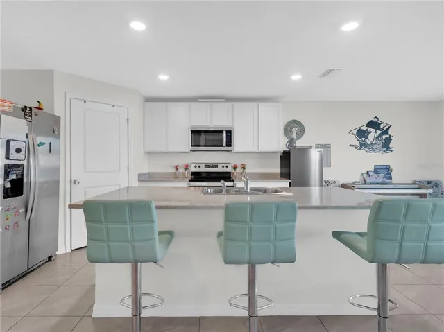 a kitchen with stainless steel appliances granite countertop a stove a sink a refrigerator a microwave a dining table and chairs