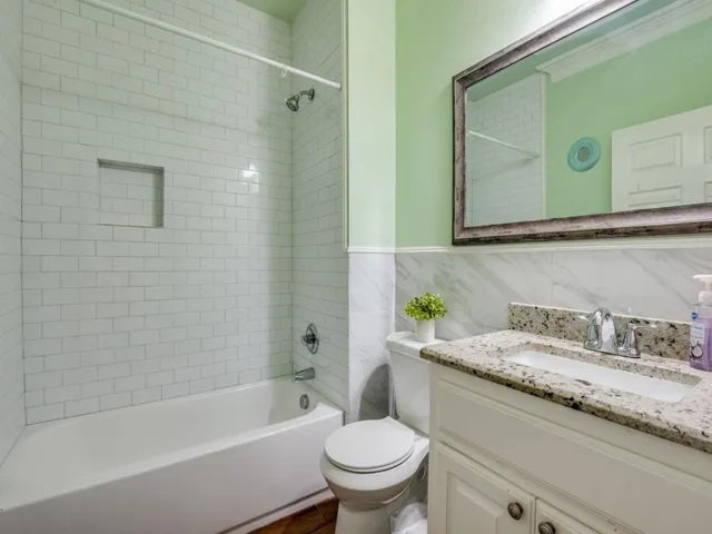 a bathroom with a granite countertop toilet sink and mirror