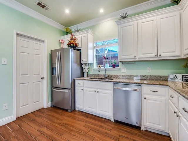a kitchen with granite countertop a refrigerator sink and cabinets